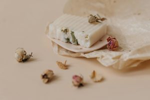 Close-up of artisanal soap with dried flowers on wax paper, eco-friendly product