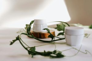 White cream jars with green leaves, elegantly arranged in a minimalist setting.