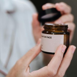 Detailed shot of hands opening a face cream jar, highlighting skincare routine.