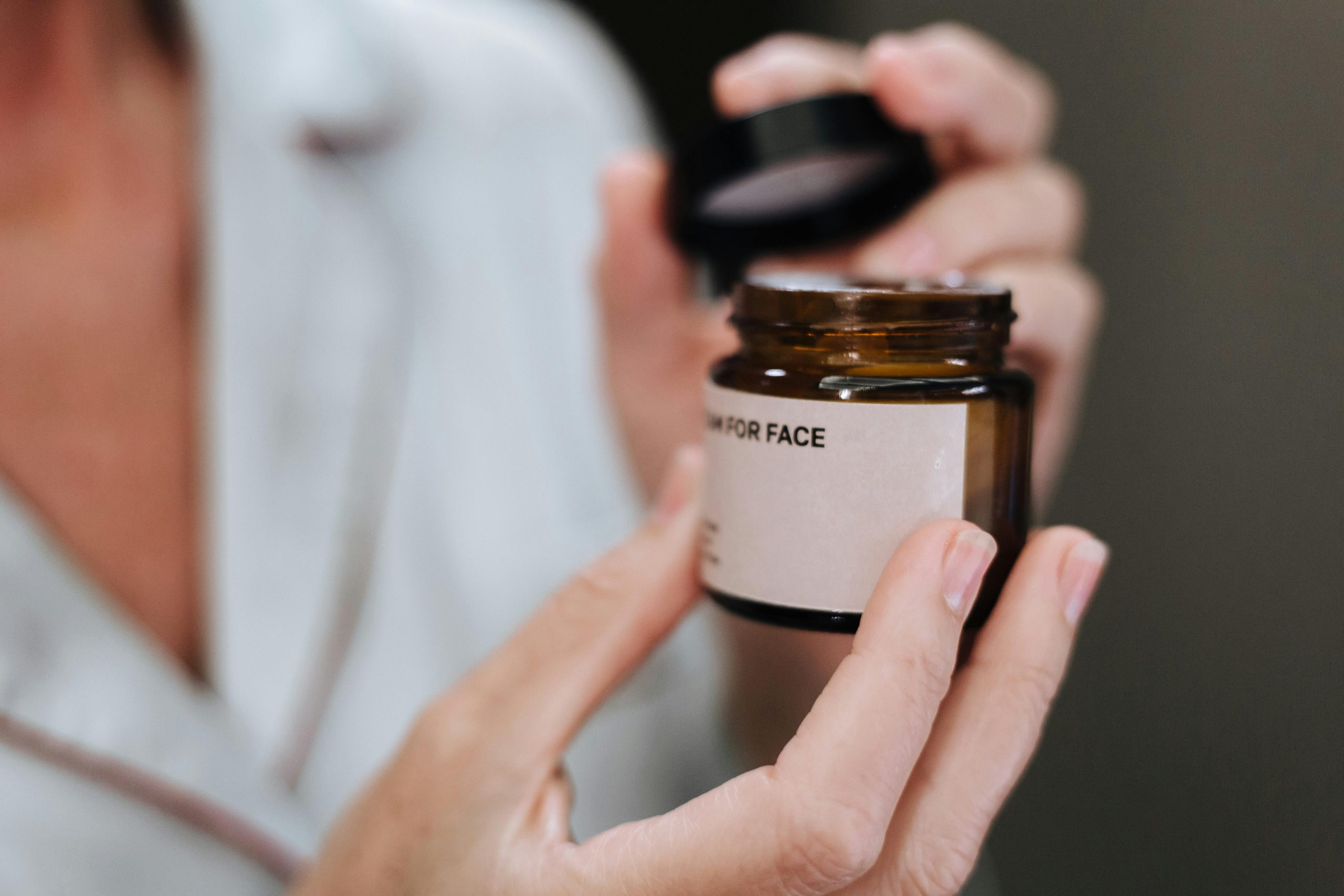 pexels photo 10221858 10221858 Detailed shot of hands opening a face cream jar, highlighting skincare routine.