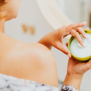 Close-up of a woman applying cream to her skin, emphasizing personal care and wellness.