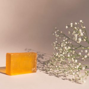 A bar of orange soap next to baby's breath flowers in a minimalist setup.