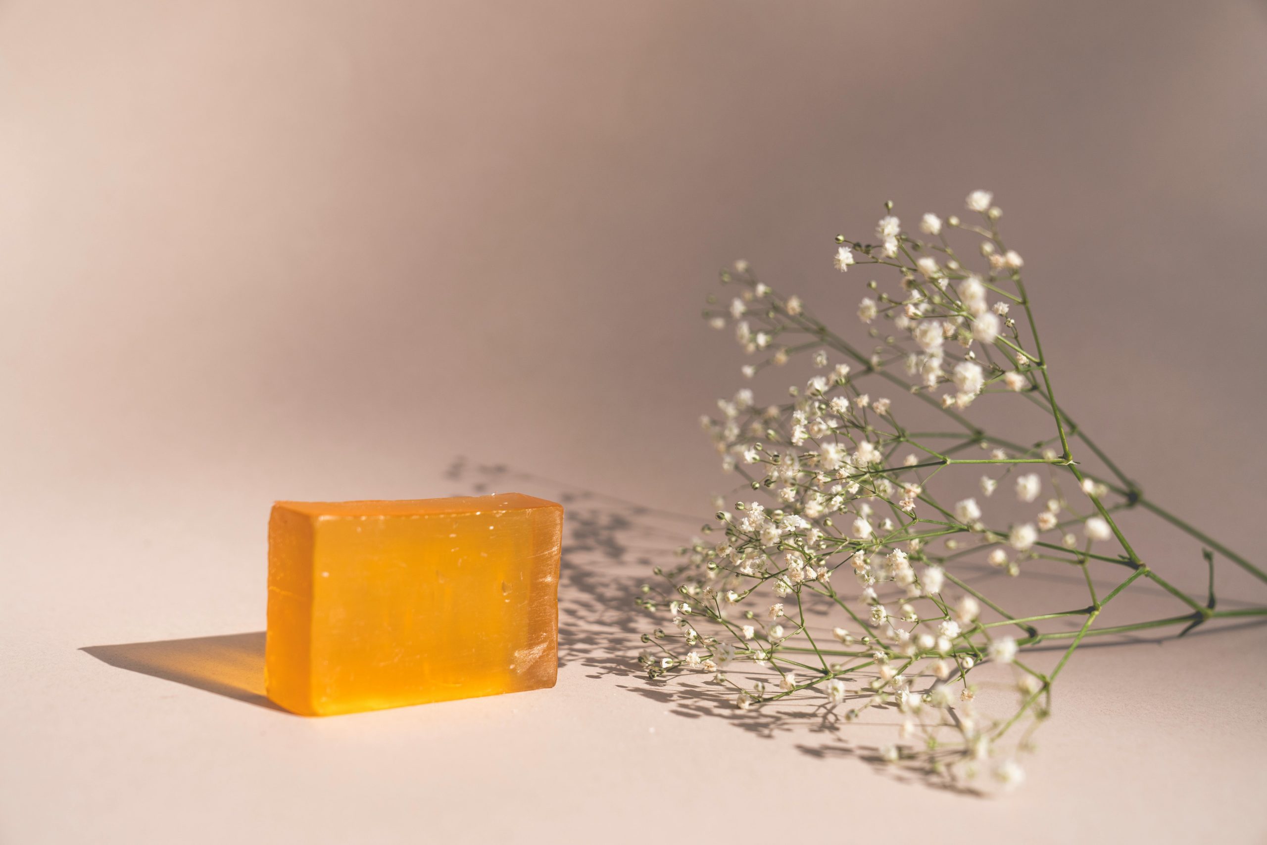 pexels photo 7615820 7615820 A bar of orange soap next to baby's breath flowers in a minimalist setup.